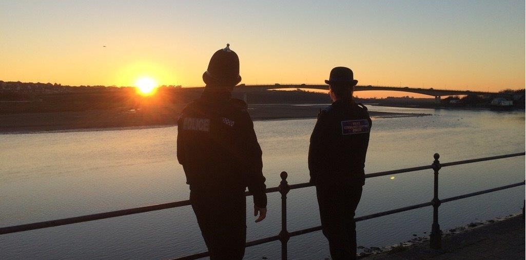 Two officers standing alongside some railings on the river front