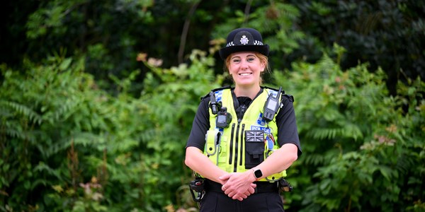 A female Special Constable smiling with trees in the background