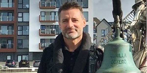 Jason Cooper in police marine unit uniform on police boat in Poole docks