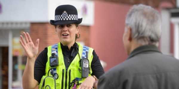 Female officer smiling and talking to a man with back turned