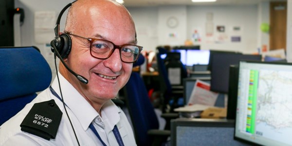 Call handler at his desk smiling to camera