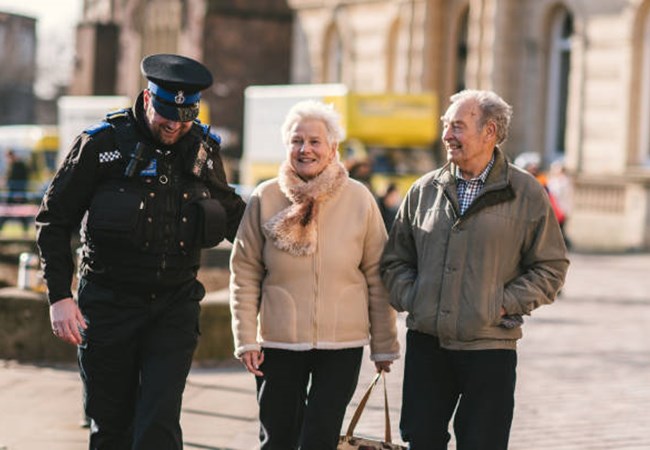 A Police Officer chatting and walking along side an elderly couple